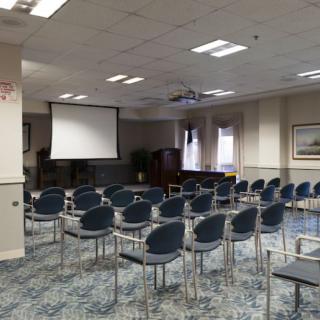 A conference room set up with rows of chairs facing a projector screen.