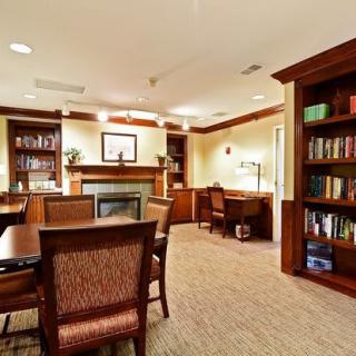 A cozy library room with bookshelves, desks, and comfortable chairs.