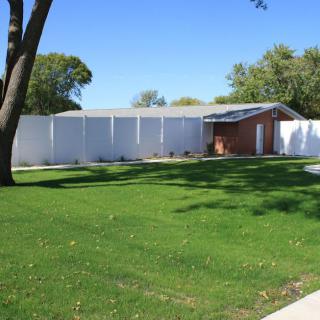 A residential house with a white fence and a well-maintained green lawn.