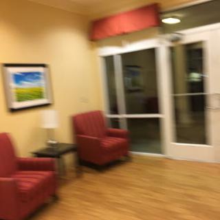 A cozy lobby area with red chairs and a colorful artwork on the wall.