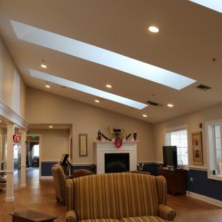A cozy living room with skylights and a fireplace, featuring comfortable seating.