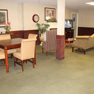 A cozy living room area with a dining table, chairs, sofas, and a television.