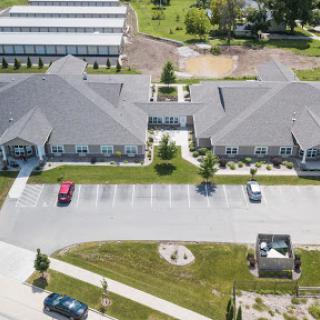 An aerial view of a modern building complex featuring a spacious parking lot and landscaped green areas.