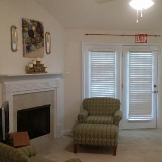 Cozy living room with a fireplace and armchairs, featuring modern decor and window blinds.