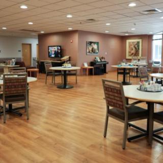 An empty dining area with neatly arranged tables and chairs on a wooden floor.