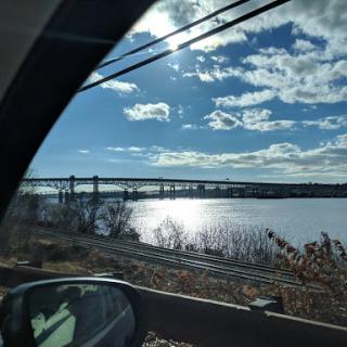 A picturesque view of a bridge over a shimmering river, framed by a clear blue sky.