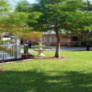 A tranquil garden scene with a tree, fountain, and well-maintained grass.