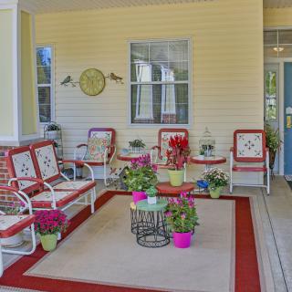 A cozy porch with comfortable seating, colorful plants, and decorative elements.