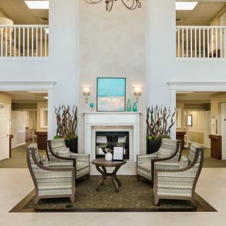 A cozy seating area with armchairs and a fireplace in a spacious lobby.