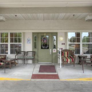 The entrance of a building with outdoor seating and large windows.