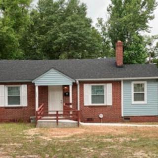 A single-story brick house with a blue accent and a spacious front yard.