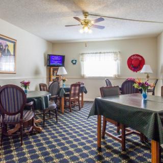 A cozy dining area with several tables and chairs, adorned with a patterned carpet and a ceiling fan overhead.