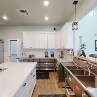 A modern kitchen with white cabinets, a spacious island, and pendant lighting over wood flooring.