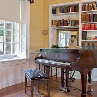 A cozy living room with a grand piano and a bookshelf filled with books.