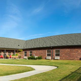 A brick building with a well-maintained lawn under a clear blue sky.
