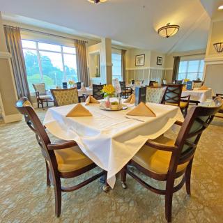 An elegantly set dining table in a spacious, well-lit restaurant with large windows.