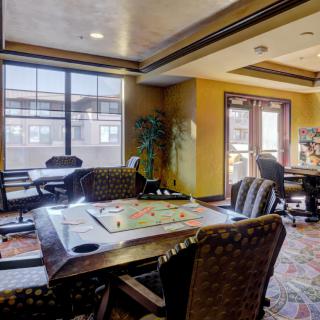 A cozy game room with a board game set up on the table and large windows providing natural light.