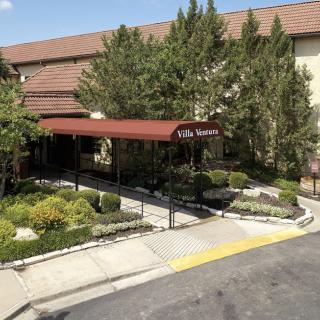 A building entrance with a red canopy and landscaped surroundings.