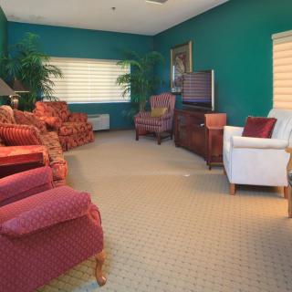 A cozy living room with teal walls, red armchairs, and a white chair, accented by lush plants.