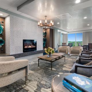 A modern living room with elegant decor, featuring a fireplace, chandelier, and comfortable seating.