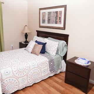 A cozy bedroom featuring a neatly made bed, stylish decor, and warm lighting.