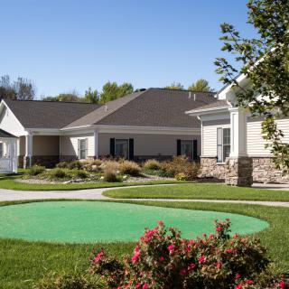A scenic view of suburban houses with well-maintained lawns and gardens under a clear blue sky.