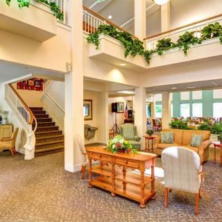 A bright and spacious lobby with comfortable seating, a staircase, and decorative plants.