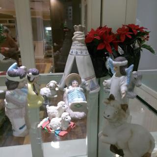 A beautifully arranged nativity scene featuring figurines, including angels and a manger, surrounded by festive poinsettias.