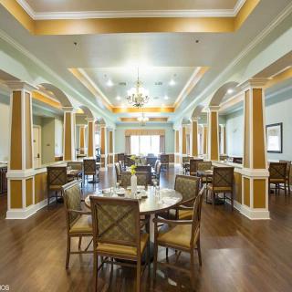 Elegant dining room with a chandelier, columns, and hardwood flooring.
