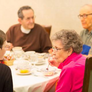 A group of seniors enjoying a meal together at a dining table.