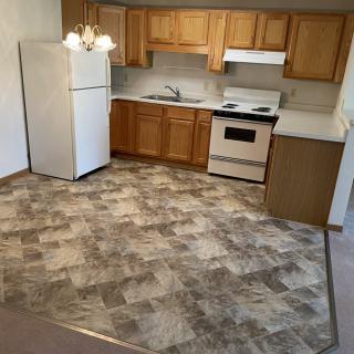 A compact kitchen with wooden cabinets, a white fridge, and stove.