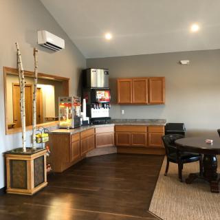 A modern kitchenette and office space featuring wooden cabinets and a round table with chairs.