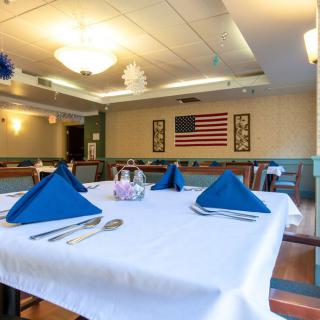A neatly set table in a restaurant with an American flag on the wall.