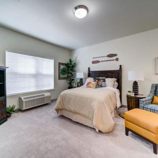 A cozy bedroom with a bed, armchair, and decorative elements.