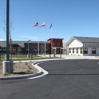 A school building with flags flying in front on a clear day.