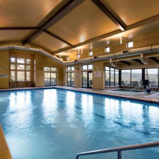 An inviting indoor swimming pool with large windows and a wooden ceiling.