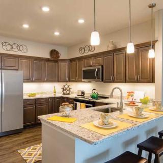 A modern kitchen with an island, pendant lights, and stainless steel appliances.