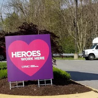 A vibrant sign that reads 'HEROES WORK HERE' promoting community appreciation.