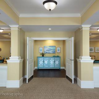 A well-lit lobby featuring a central blue cabinet, decorative artwork, and elegant pillars.