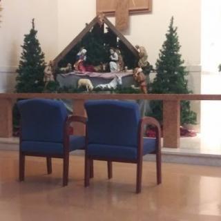 A cozy setting featuring two chairs in front of a Christmas nativity scene.