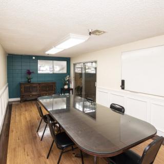 A modern meeting room with a long conference table and chairs, featuring wooden flooring and a decorative wall.