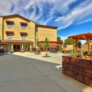 A welcoming hotel exterior featuring outdoor seating and a clear blue sky.