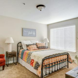 A cozy bedroom with a metal bed frame, colorful quilt, and soft lighting.