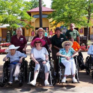 A joyful group of seniors in wheelchairs enjoying a day out with their caregivers.