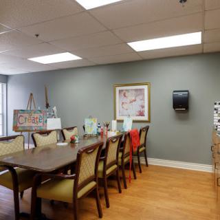 A spacious dining area featuring a long table with chairs, complemented by wall art and bright lighting.