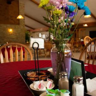A cozy restaurant table setting with flowers and condiments.