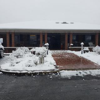 A snow-covered house and driveway during winter.