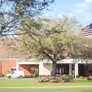 A building with an American flag, trees, and a parked vehicle in front.