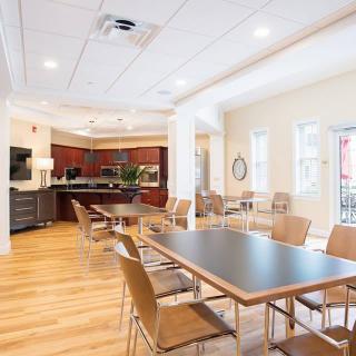 A modern dining area with a kitchen, featuring wooden floors and contemporary furniture.