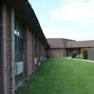 A brick building with a sloped roof and a green lawn in front.